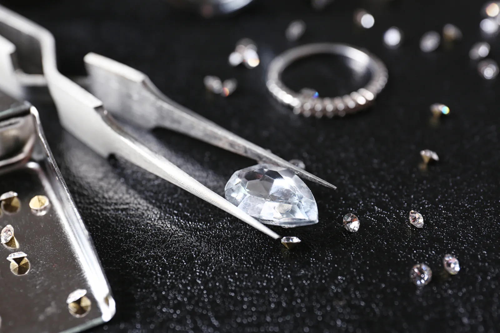 Diamant wird mit einer Pinzette begutachtet